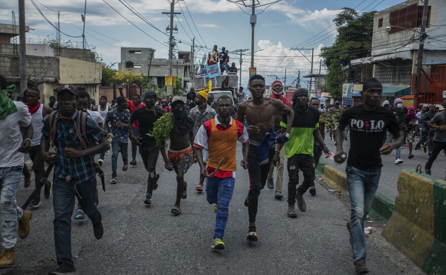 Protesters calling for the resignation of Haitian Prime Minister Ariel Henry run after police fired tear gas to disperse them in the Delmas area of Port-au-Prince on Oct. 10.