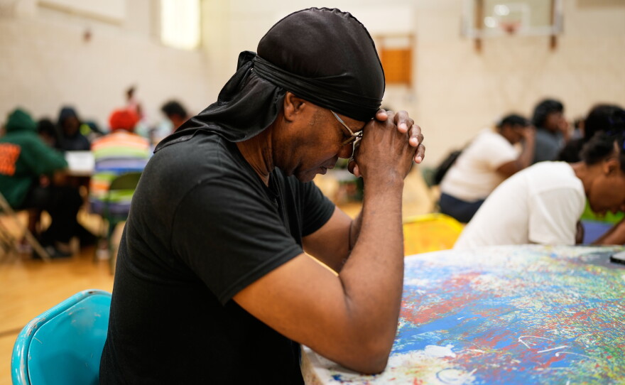 A person prays before receiving a free boxed lunch at City Life Center in Gary, Ind., Thursday, Aug. 20, 2026, more than a week after a deadly storm passed through the area.