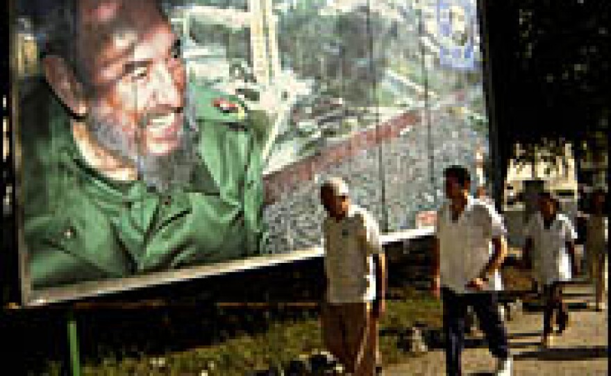 Cubans pass by a poster of President Fidel Castro on their way to work early Tuesday. Castro resigned Tuesday as president and commander in chief of Cuba.