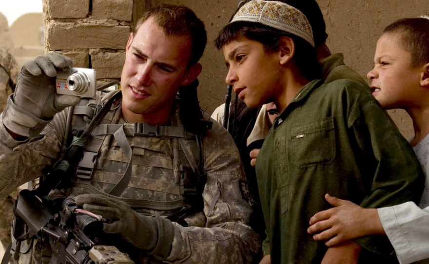 Afghan boys crowd around a U.S. soldier in Kandahar province to see photos he's taken; July 28.