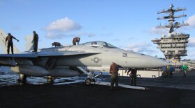 Airmen maintain an F/A-18E Hornet, flown by Strike Fighter Squadron 14 (VFA-14), aka "The Top Hatters," aboard the USS Nimitz.