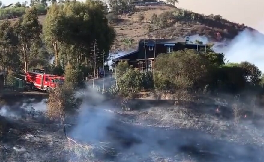 Firefighters putting out the flames surrounding a house in Rainbow during the Aruba Fire, Sept. 5, 2021.