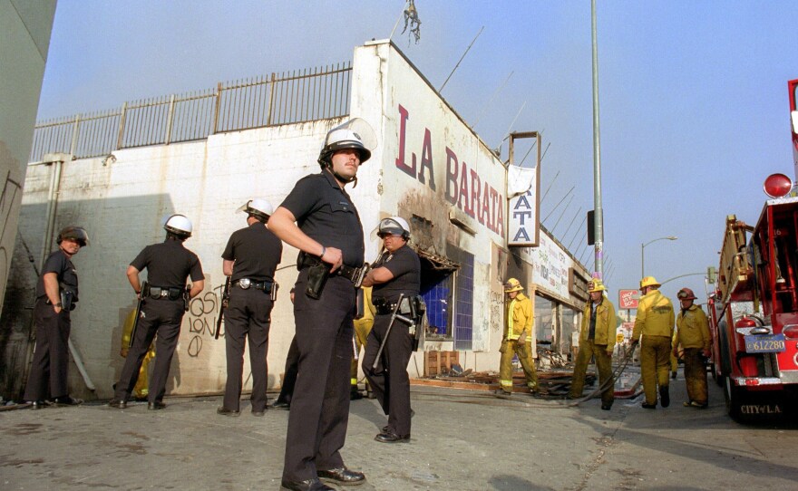 Los Angeles police officers in riot gear stand guard at a grocery store that had been burned down near downtown Los Angeles on April 30, 1992.