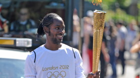 FILE — Torchbearer Jason Arday carries the Olympic Flame on the Torch Relay leg between Sutton and Merton, in London, July 23, 2012.