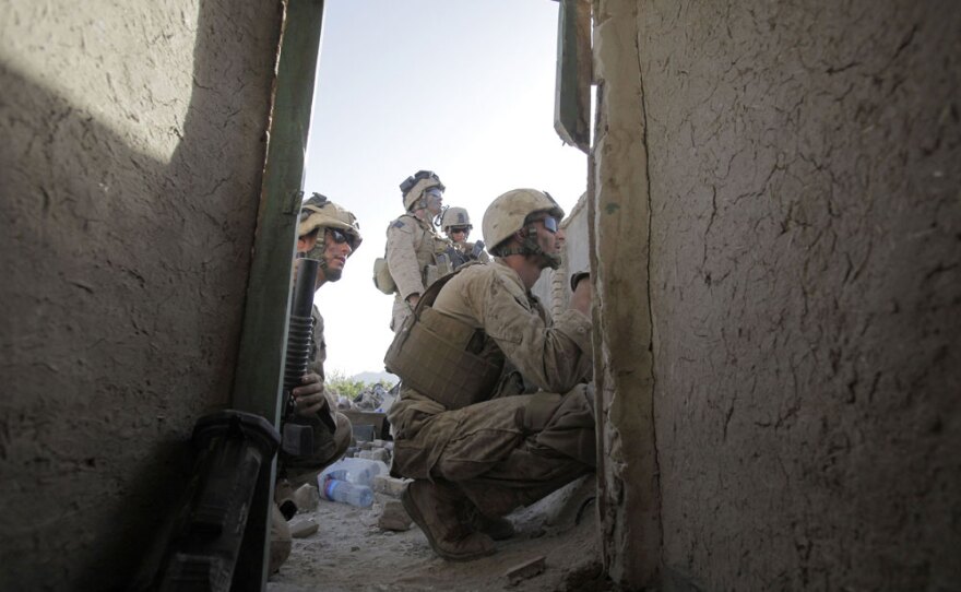 U.S. Marines from Golf Company, 2nd Batallion, 3rd Regiment, 2nd MEB, 2nd MEF, peer through a hole in a wall on the rooftop of a house in Dahaneh to look for Taliban snipers on a mountainside Wednesday in southern Afghanistan.