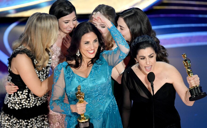 Producer Melissa Berton (center) and director Rayka Zehtabchi (right) accept an Oscar for their documentary 'Period. End of Sentence.'