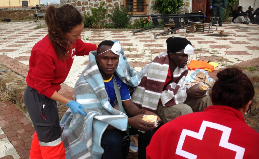 Red Cross medics treat African migrants on arrival in Ceuta. Many travel across the Mediterranean Sea by inflatable raft, or by swimming around a border fence from Morocco. Others scale the fence or cross the border hidden in trucks or cars.