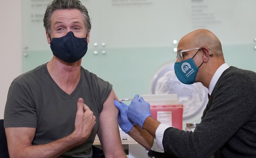 Gov. Gavin Newsom, left, receives a Moderna COVID-19 vaccine booster shot from California Health and Human Services Secretary Dr. Mark Ghaly at Asian Health Services in Oakland, Calif., Wednesday, Oct. 27, 2021.
