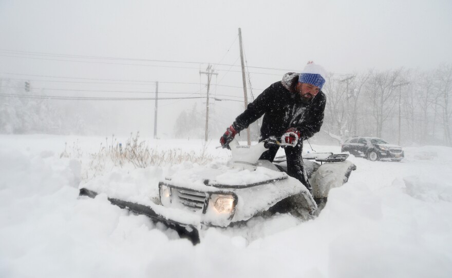 Robert Skimin uses an ATV to dig out after an intense snowstorm.