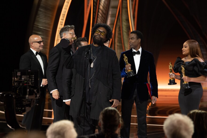 Chris Rock (right) presents the Oscar® for Documentary Feature to David Dinerstein, Robert Fyvolent and Ahmir "Questlove" Thompson (center) during the live ABC telecast of the 94th Oscars® at the Dolby Theatre at Ovation Hollywood. March 27, 2022. 