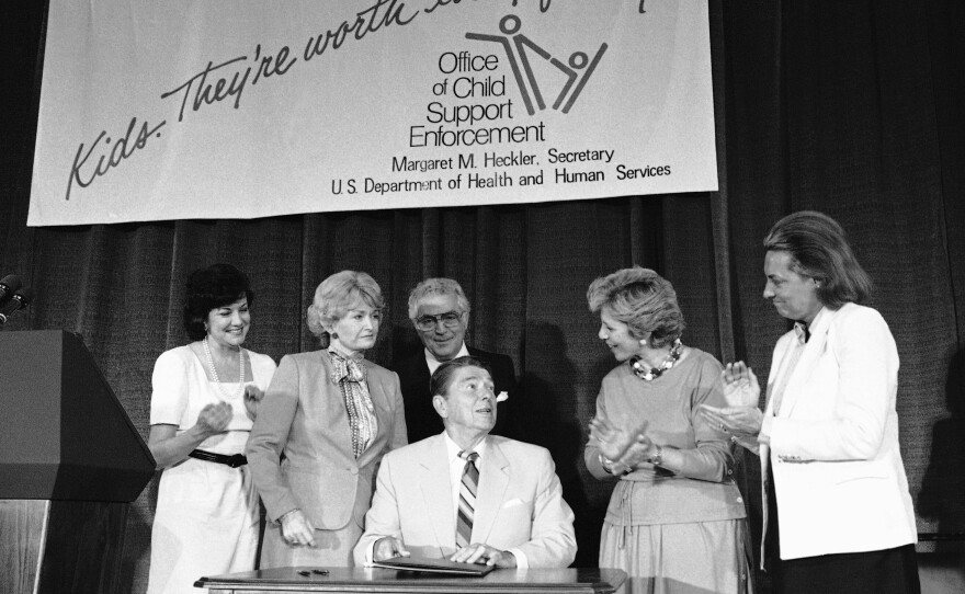 President Ronald Reagan signs legislation providing for the mandatory withholding of wages from parents delinquent in child support payments, as well as settling rules about foster care repayment, in 1984.