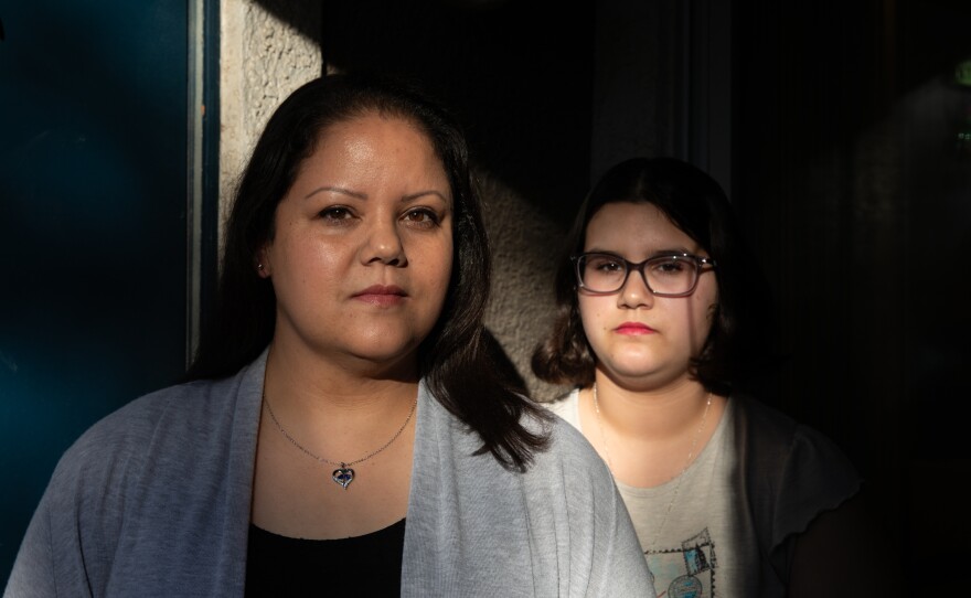 Amber Ayala stands with her daughter outside their home in Las Vegas.