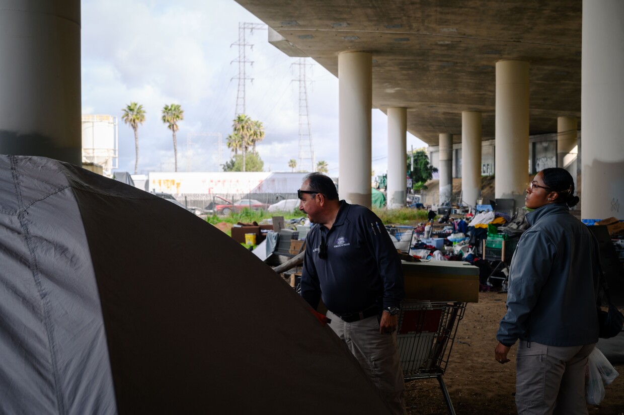 Qiana Williamson and Hector Hueso, the two members of National City’s HOME team, talk with residents experiencing homelessness under the I-5 freeway in National City, California on March 7, 2024. National City is the second in San Diego County to move away from a police-led response to homelessness and toward trained caseworkers.
