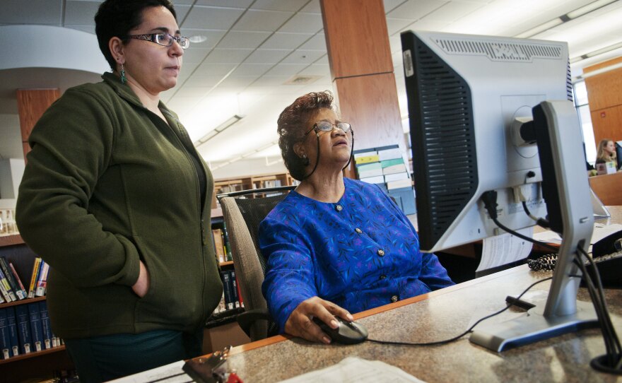 Sims-Wood goes over computer data with librarian Maria Bonet. Though Sims-Wood is on the job at a time when she thought she would be retired, she stays positive. "I have faith that things will work out. I don't care how bad they are. It's going to work out," she says.