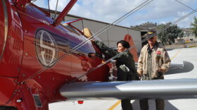 Photo of host Elsa Sevilla climbing aboard an antique 1943 Stearman, one of 600 Stearman planes left in the entire world, with pilot Bob Simon. 
