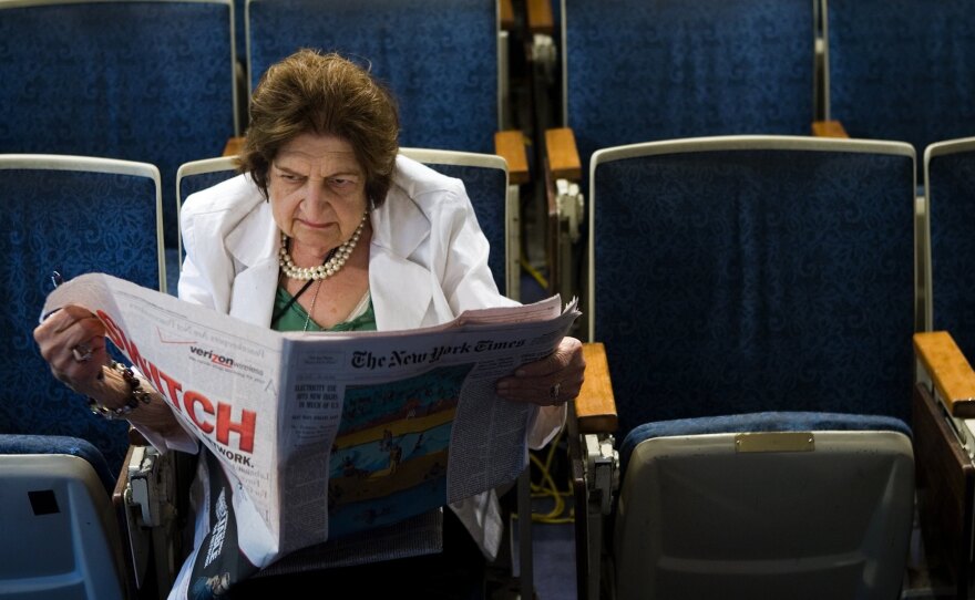 Helen Thomas reads the newspaper while sitting in her chair in the White House press room in 2006. She died on Saturday at age 92.