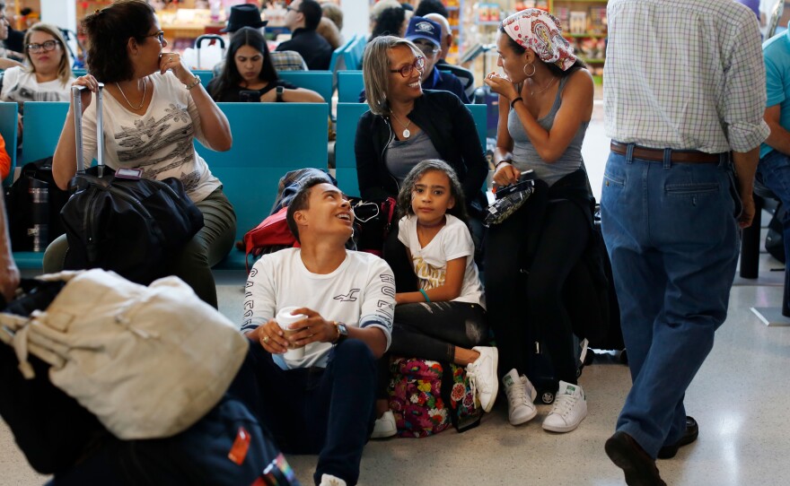 Glisela Vega Rivera and her three children wait to board a flight to Miami. The family is relocating to Doral, Fla., where her two older kids will start school at Ronald W. Reagan/Doral High School next week.