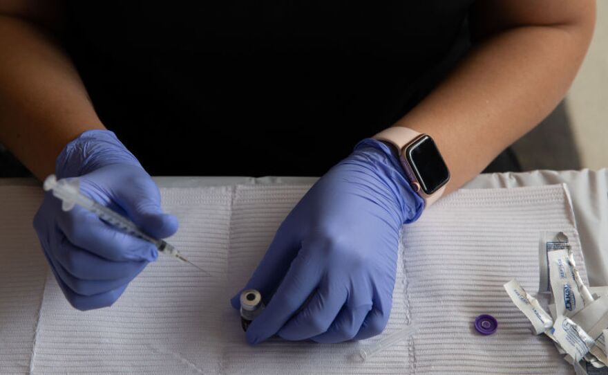A health care worker fills syringes with doses of the COVID-19 vaccine on Aug. 24 at the Southfield Pavilion in Southfield, Mich.