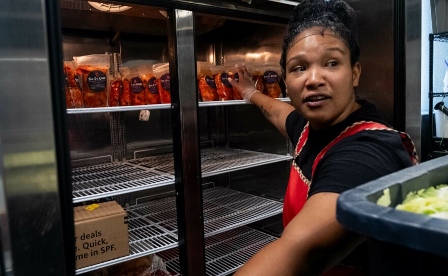 Cunningham sorts through packaged kimchi in the fridge.