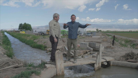 RESOLVE TO SOLVE Host Miles O'Brien and farmer Reid Fishering walk the plank over the irrigation ditch, which is the lifeline for his sweet corn farm. (Delta, CO)