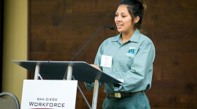 Tania Sanchez-Aguilar speaking behind a lectern at a San Diego Workforce Partnership event. 