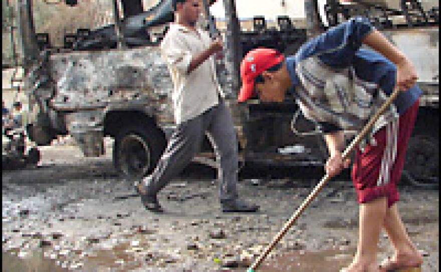 Iraqi youth Wednesday clean up the wreckage left behind in Baghdad by a car bomb that exploded on Tuesday.