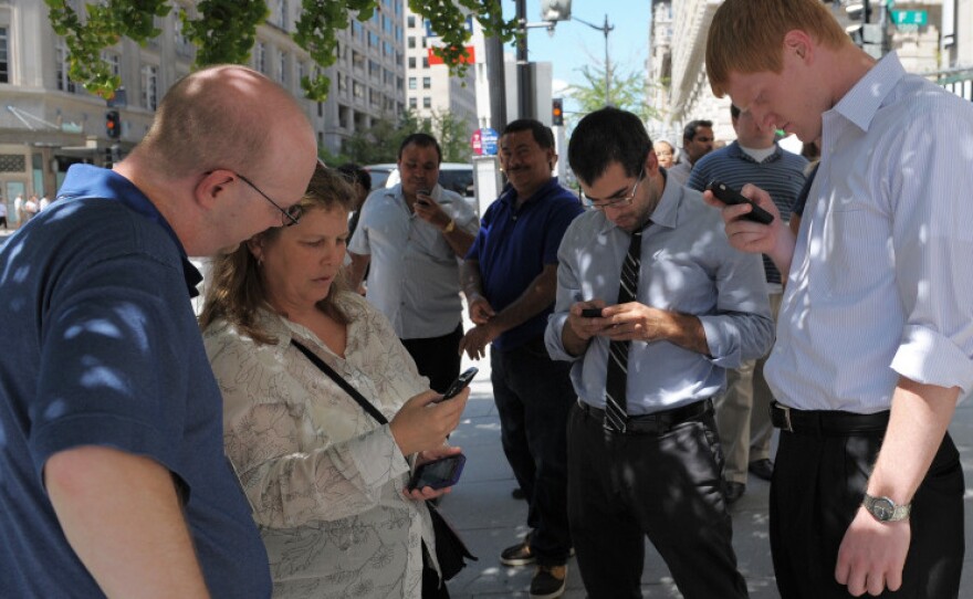 People check their smartphones while standing in the street shortly after an earthquake struck Washington on Tuesday.