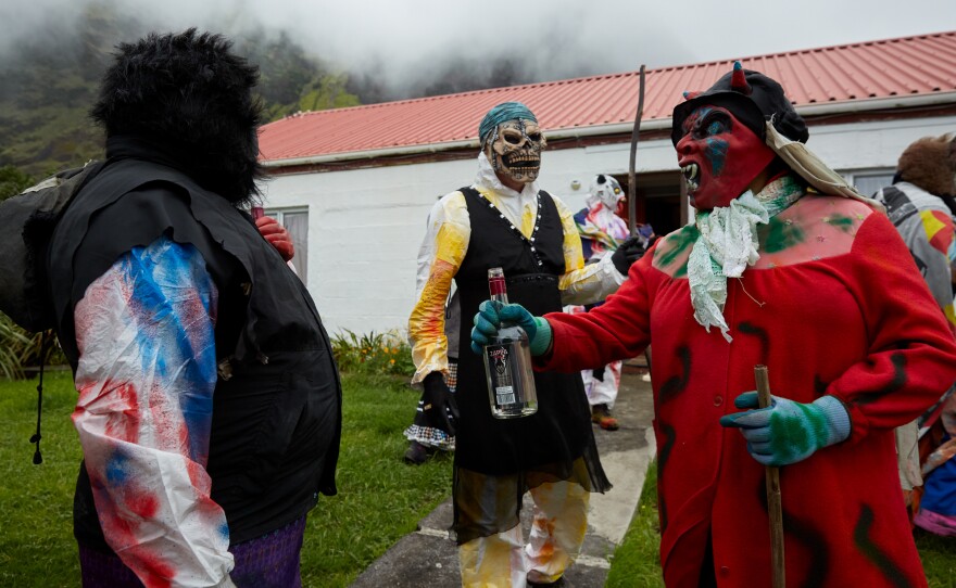 A group of Okalolies share a drink while on a break from roaming around the village. The Okalolies are often invited for a drink by "brave" members of the community who open their doors to the group. Many are also fathers and will pass by their own houses during the day's festivities.