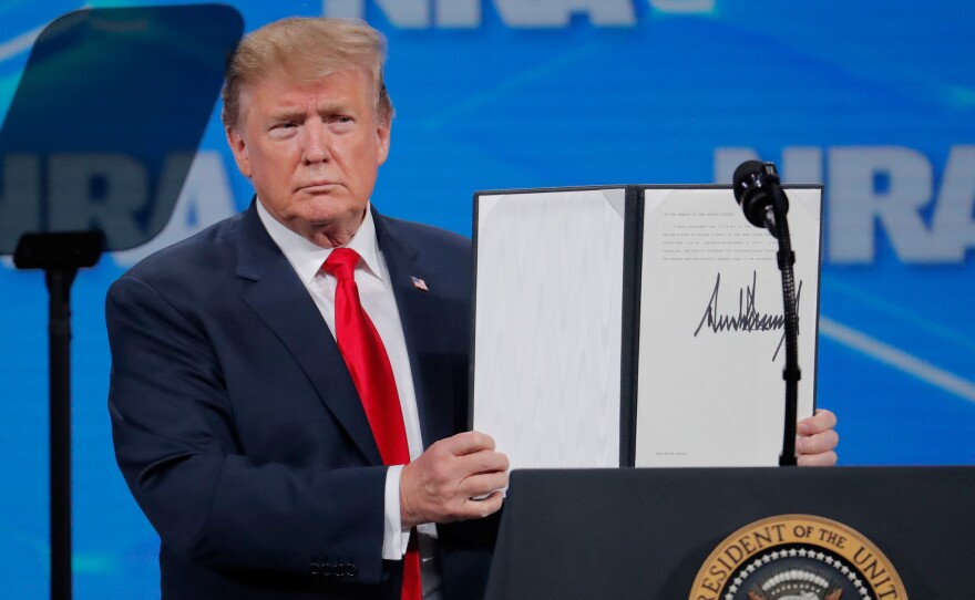 President Trump holds up an executive order he signed at an NRA event Friday, announcing that the United States will drop out of the Arms Trade Treaty that was signed during the Obama administration.