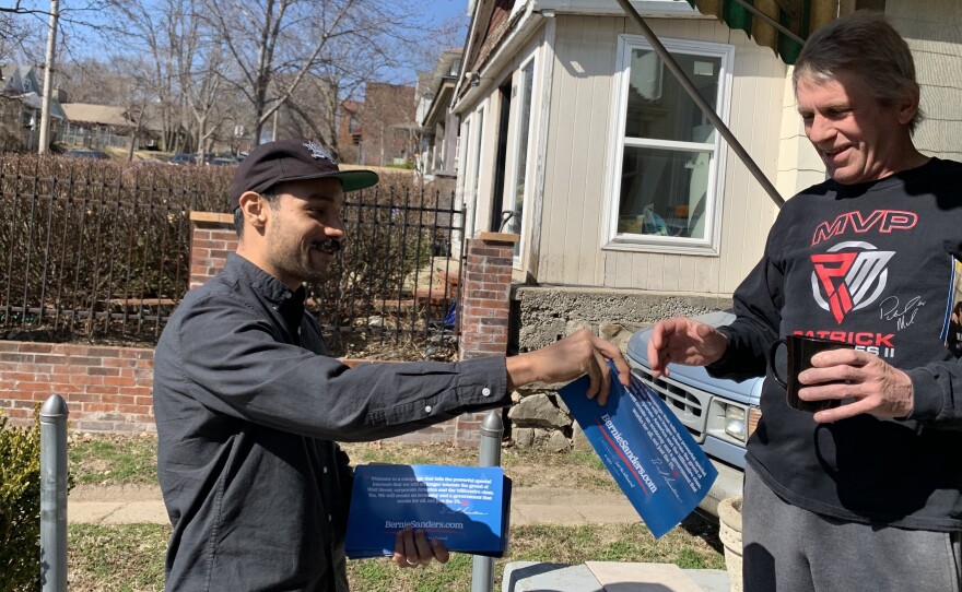 Ricardo Flores, a volunteer for Bernie Sanders, hands John Rellihan a campaign flyer in North Kansas City, Mo., on Sunday. Sanders' supporters are making a big push for him to regain front-runner status.