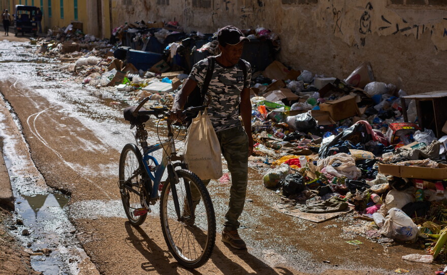 A man pushes his bicycle along a trash-strewn street in Havana, Cuba, Tuesday, June 9, 2026.