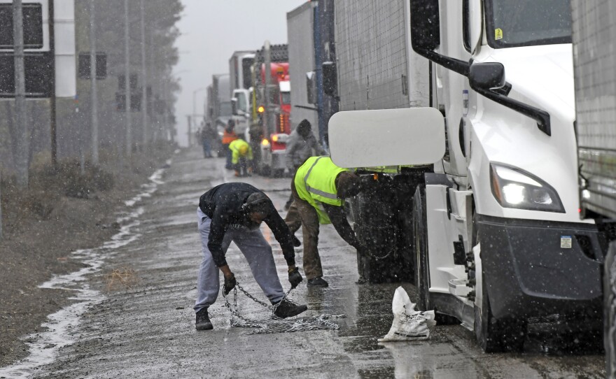 A long line of trucks are parked off the west bound I-80 as drivers put chains on the truck wheels in preparation for the snow storm over the Sierra Nevada on Thursday, Feb. 29, 2024, in Lake Tahoe, Calif.