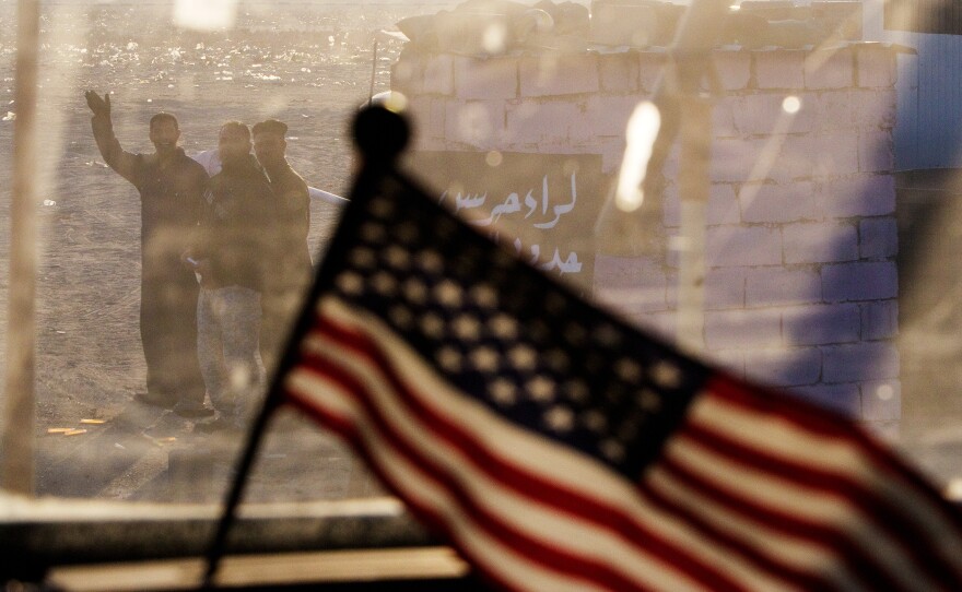 Iraqis wave at a departing U.S. armored vehicle from the 3rd Brigade Combat Team, 1st Cavalry Division. The vehicle was part of the last U.S. military convoy to leave Iraq on Dec. 18, 2011. Iraq was relatively stable at the time the U.S. pulled out, but the rise of the Islamic State would lead President Obama to launch an air campaign in Iraq in August 2014.