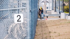 County Supervisors Tara Lawson-Remer and Paloma Aguirre peak through the fence after being denied for a pre-approved inspection at the CoreCivic Detention facility in Otay Mesa, February 20th, 2026.