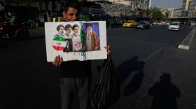 A man displays a placard with portraits of the current and late supreme leaders and the late Revolutionary Guard Gen. Qassem Soleimani at the Islamic Revolution Square in downtown Tehran, Iran, Saturday, July 18, 2026.