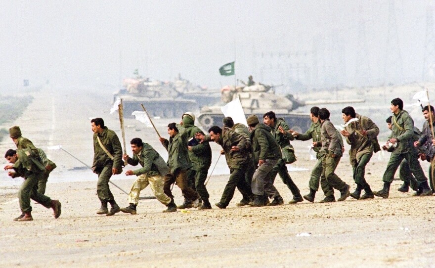 Iraqi soldiers cross a highway carrying white surrender flags on Feb. 25, 1991, in Kuwait City. The U.S.-led coalition overwhelmed the Iraqi forces and swiftly drove them out of Kuwait.