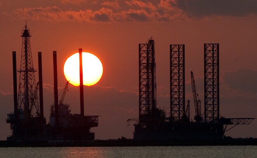 The energy industry was shaken by a trio of events this week that could help shape the future of oil and gas. Here, the sun sets behind two under-construction offshore oil platform rigs in Port Fourchon, La., in 2010.