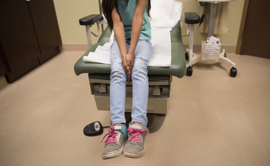 A young girl waits for care in a medical clinic. A growing number of citizen children of immigrant parents are losing out on Medicaid because their parents fear deportation.