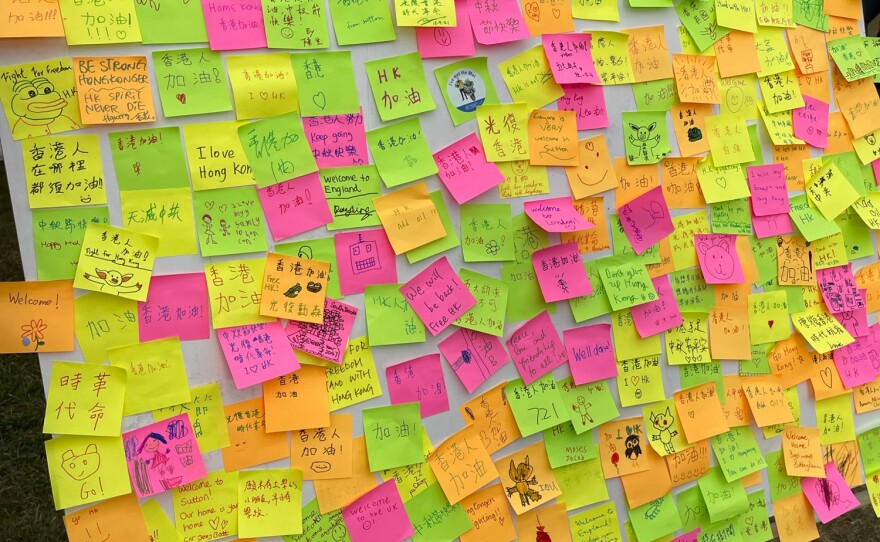 Sutton residents and newcomers from Hong Kong trade messages of welcome and calls for freedom using colored sticky notes. The message board recalls a similar one created along a wall in Hong Kong during its 2014 democracy protests.