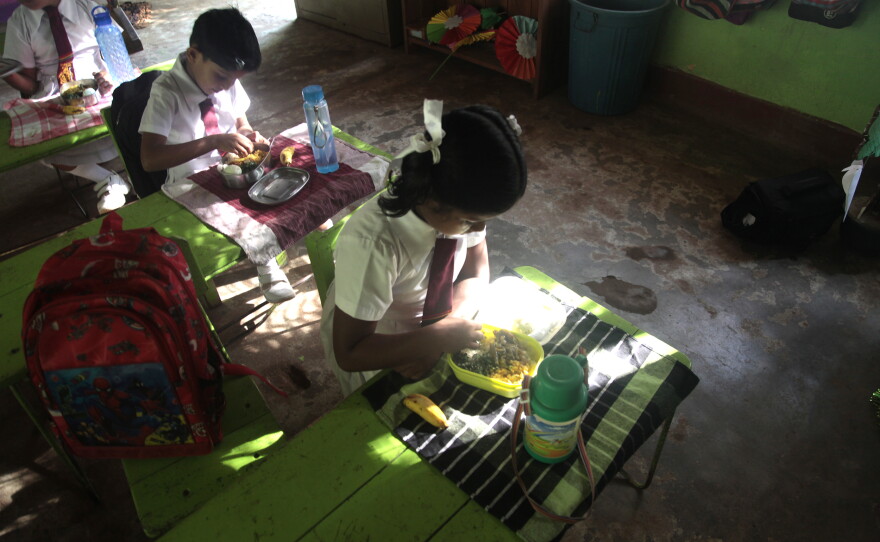 School children eat the fresh meal of rice, okra curry, egg and daal that Nilanthi Kumari has prepared for kids at the  local public school in the town of Sigriya in central Sri Lanka. Kumari says the government pays her about 35 cents per meal — but with rising costs caused by the Mideast war, she's barely breaking even — and she's thinking about walking away from this job, which keeps vulnerable children nourished.