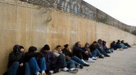 Mexicans preparing to cross illegally into the U.S. usually wait for nightfall. Here, a group sits along the border fence in Tijuana, Mexico, in 2008.