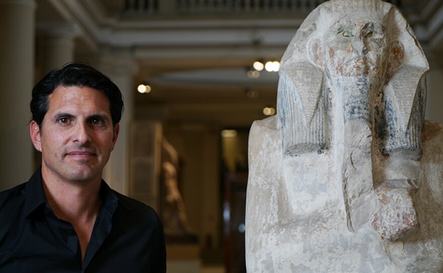 Presenter Darius Arya with a statue of King DJoser, who was buried in the Step Pyramid at Saqqara, Egypt.