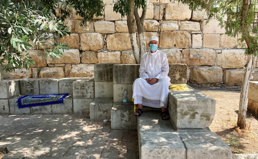 Mustafa Abu Sway, on the Al-Aqsa Mosque advisory council, sits outside the mosque next to his yellow carpet. Worshipers are asked to bring their own prayer carpets from home now. Abu Sway says he's never laundered so many carpets in his life.