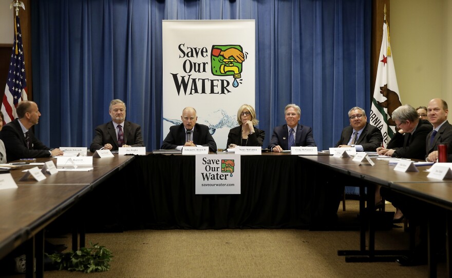 California Gov. Jerry Brown, middle, talks to reporters after a three-hour meeting on the drought with agricultural, environmental and urban water agency leaders from across California. Brown introduced statewide water cutbacks earlier this year.