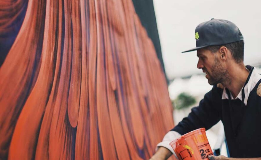 A photo of an artist painting a mural at the Kaaboo music and arts festival.