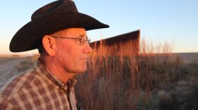 Alfalfa grower Craig Miller stands beside the border wall at Ft. Hancock, Texas. Undocumented immigrants and drug smugglers are known to cross here regularly through gaps in the wall on either side of town. 