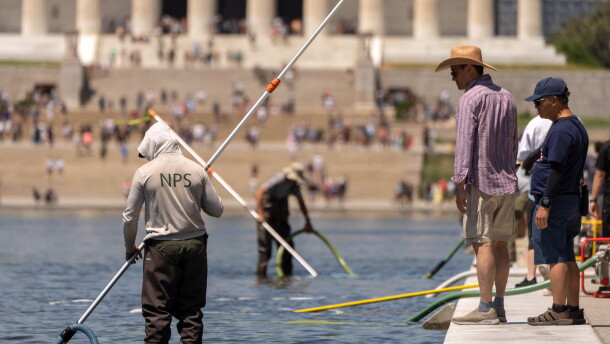 Visitors watch as National Park Service employees use vacuums to clean the Lincoln Memorial Reflecting Pool, Saturday, June 20, 2026, in Washington.