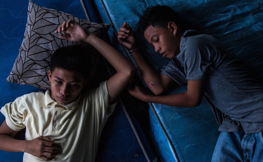 Chino, left, and his friend Tito cool off at a gang house in San Pedro Sula. Chino joined a gang at 14 and has the privileges that come with being a member: respect, fear, power — but also "a cell phone and chains," says Ayuso. Ayuso also heard Tito — who is not in a gang — say he hopes to be like Chino someday.
