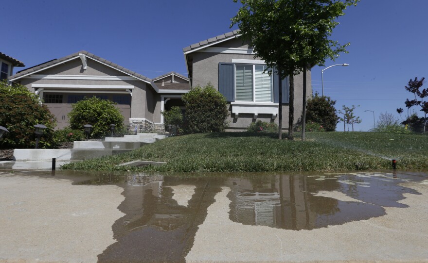 Water flows down a sidewalk from water sprinklers running at a home Thursday, April 2, 2015, in Rancho Cordova, Calif.