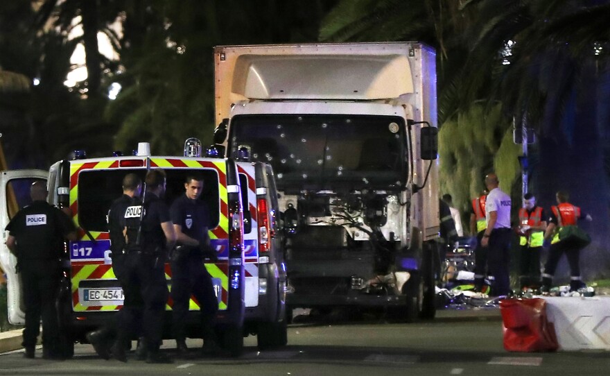 Police officers and rescue workers stand near a van that drove into a crowd in Nice on Thursday evening. The former mayor of the French city of Nice said dozens of people were killed in the attack Thursday. He urged residents to stay indoors.